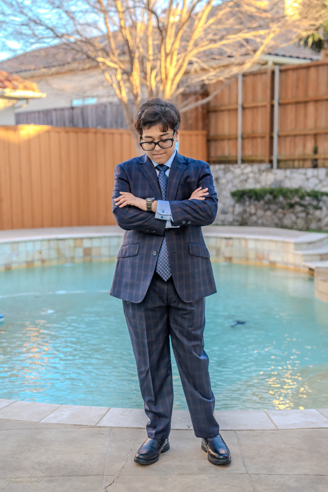 Ashank in a navy suit, arms crossed, by the pool